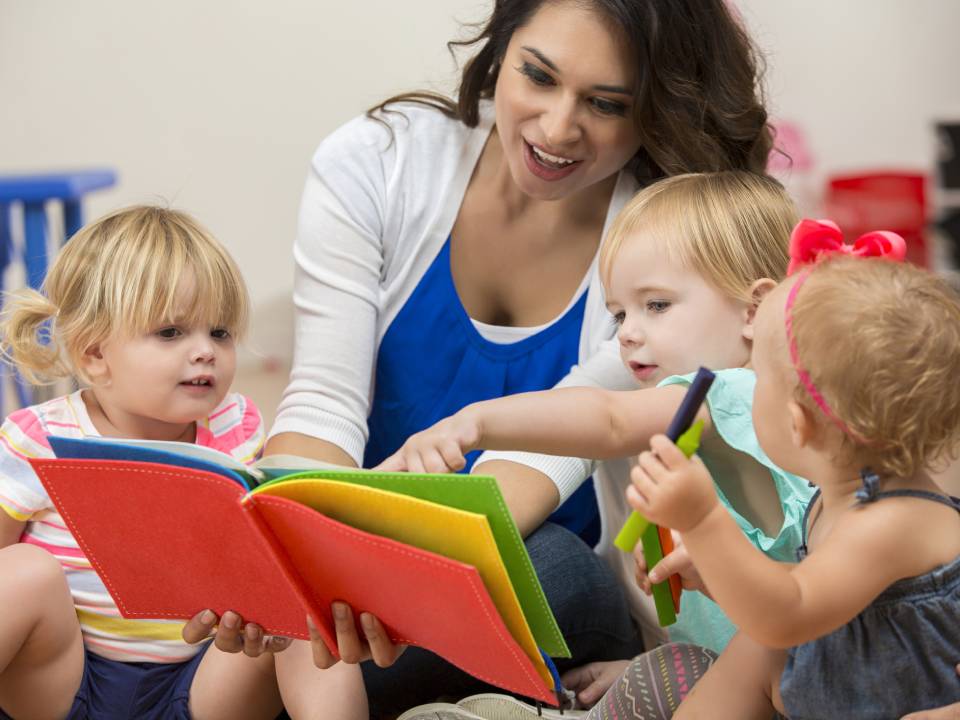 przedszkolanka czytająca książkę dziecom